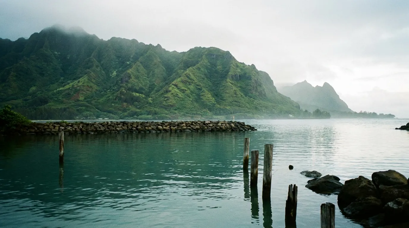 Green mountain ridges meeting calm harbor water in morning light on Maui’s north shore