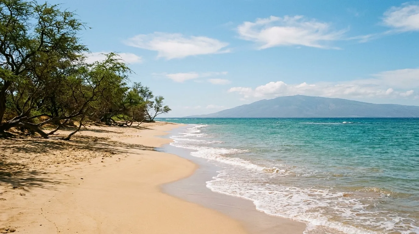 Turquoise waves washing onto an empty golden-sand beach on Maui’s south shore